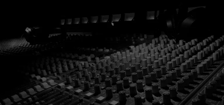 Black and white close-up of a large recording console, the nerve center of a music production studio.