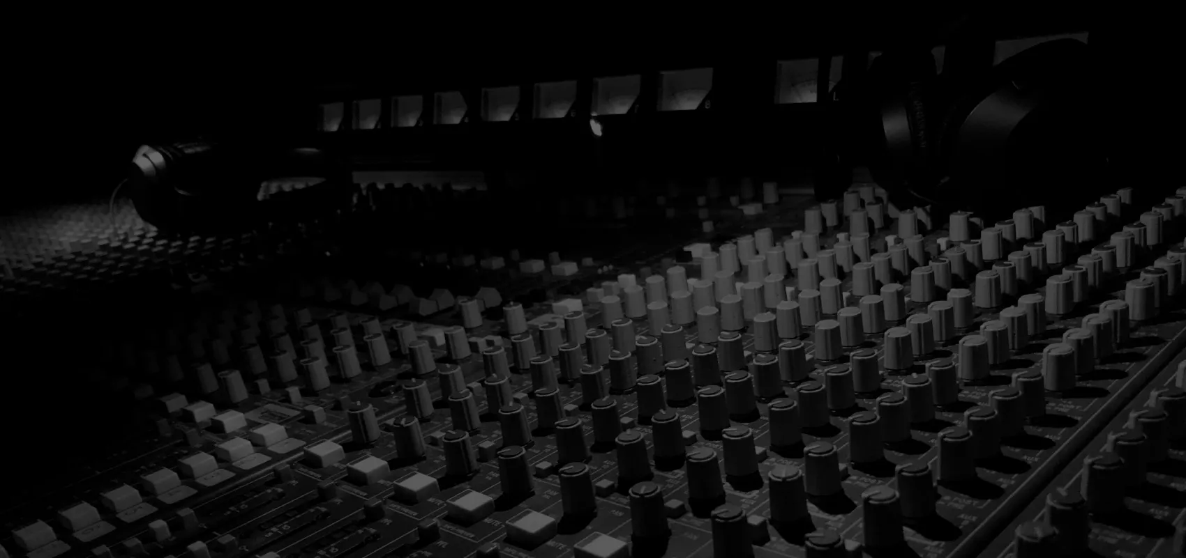 Black and white close-up of a large recording console, the nerve center of a music production studio.